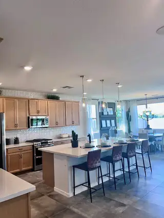 Spacious kitchen with light wood cabinets, a large island, modern lighting, and a dining area with ample natural light.