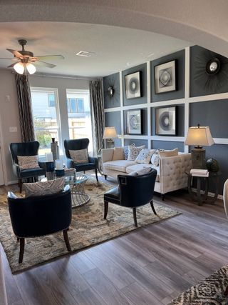 A stylish living room with tufted sofas, elegant armchairs, modern artwork, and warm lighting on wooden floors.