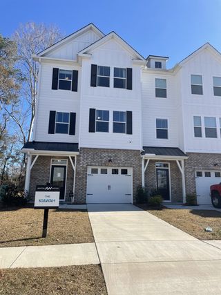 Street view A charming white townhouse with classic shutters in Village Club at Wescott by Ashton Woods, Summerville, SC.