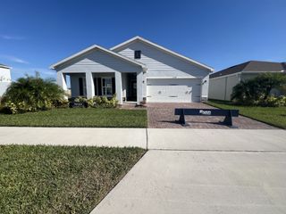 A charming light gray home with a brick driveway in Laurel Glen by Ryan Homes (Haines City, FL).