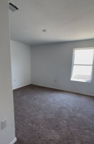 Model Home An airy, carpeted room with soft natural light and white walls, perfect for customization and comfort.