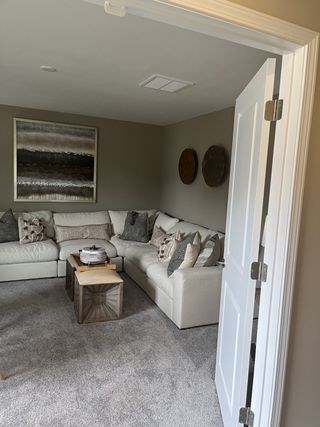 A cozy living room featuring a plush sectional sofa, neutral tones, and artistic wall decor for a relaxing atmosphere.