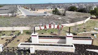 A scenic entrance to Lariat 60' by Coventry Homes in Liberty Hill, TX, featuring a well-designed community layout and signage.
