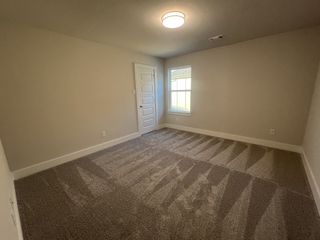 A cozy bedroom featuring plush carpeting, soft neutral walls, and a bright window with ample natural light.