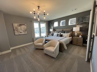 A spacious master bedroom with a chandelier, large windows, and a stylish king-size bed.