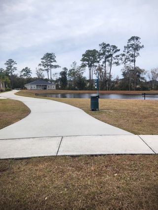 A scenic walking path by a serene pond and trees in Panther Creek by Brightland Homes, Jacksonville, FL.