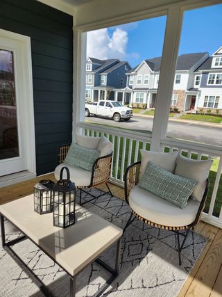 A cozy porch with elegant wicker chairs, soft cushions, and lanterns on a stylish coffee table, perfect for relaxation.