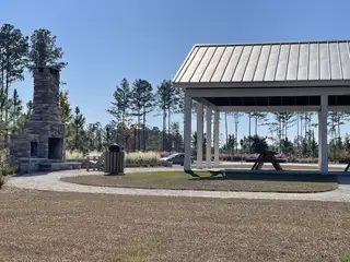 Community Amenities A scenic outdoor pavilion with a stone fireplace in Pine Hills at Cane Bay by D.R. Horton (Summerville, SC).