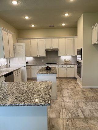Elegant kitchen with granite countertops, white cabinets, and recessed lighting, ideal for culinary creativity.