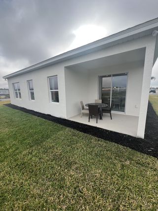 A sleek white home with a cozy patio and manicured lawn in Ashton Covey by Ryan Homes (Winter Haven, FL).
