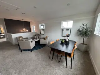 Model Home A cozy living space with a stylish black accent wall, elegant chandelier, and modern dining area with warm tones.