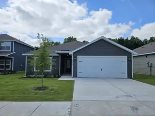 Street view A charming gray home with a spacious driveway and lush lawn in College Park by LGI Homes (Dallas, TX).
