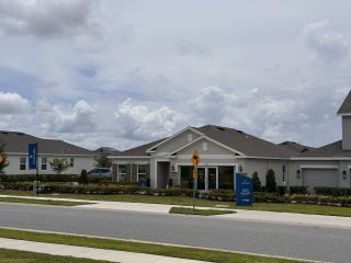 Street view A modern white home with a manicured lawn in Trinity Lakes by Landsea Homes (Groveland, FL).