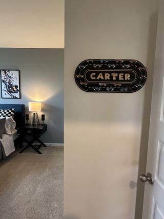 A cozy bedroom with a sports-themed sign, stylish wall art, and ambient lighting for a kid-friendly space.