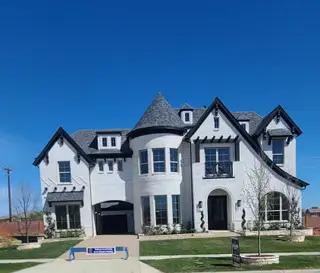 A grand white brick home with turrets and lush landscaping in Silverleaf Estates by Grand Homes (Frisco, TX).