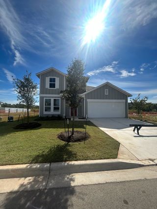 Street view A newly built two-story home with a manicured lawn and bright exterior in Harvest Ridge by Brohn Homes (Elgin, TX).