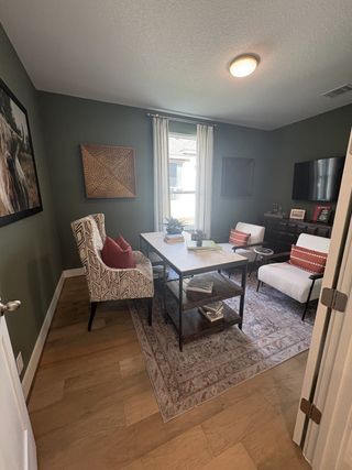 Model Home A cozy home office with earthy tones, a patterned armchair, sleek desk, and plush area rug for a stylish and functional space.