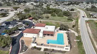 An inviting community center with a pool and parking in The Grove at Vintage Oaks by Scott Felder Homes (New Braunfels, TX).