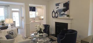 A cozy living room with a modern fireplace, elegant decor, and an open view into a bright kitchen with pendant lighting.