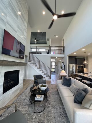 Model Home A modern living room with high ceilings, sleek fireplace, cozy seating, and stylish decor.
