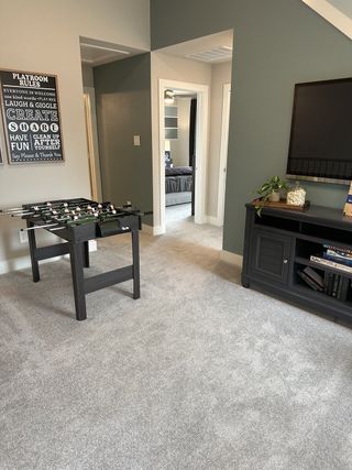 A cozy playroom with plush carpeting, a foosball table, and modern decor, perfect for relaxation and fun.