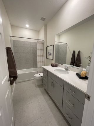 Modern bathroom with sleek gray vanity, spacious countertop, tiled bathtub, and warm lighting.