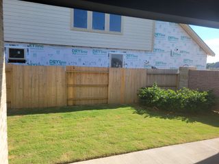 A new build with a wooden fence and green lawn in Fulbrook on Fulshear Creek 60' by Perry Homes (Fulshear, TX).