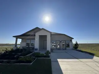 Street view A modern stone exterior home with a manicured yard in Waterstone: Stonehill Collection by Lennar (Kyle, TX).