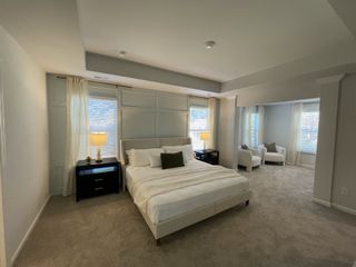 A spacious bedroom with soft carpet, elegant bed, cozy seating area, and large windows for natural light.