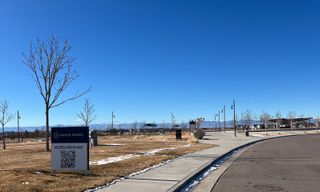A scenic view of a sidewalk lined with trees and mountains in Painted Prairie by Tri Pointe Homes, Aurora, CO.
