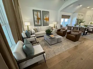 A cozy living room featuring plush seating, contemporary art, and elegant decor with a view into the modern dining area.