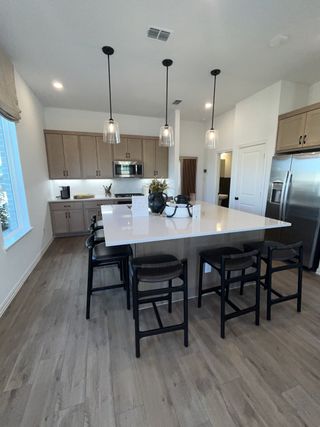 A modern kitchen with wood cabinets, sleek countertops, and pendant lighting over a spacious island with bar seating.