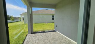 A cozy covered patio with a paver floor and a backyard view, perfect for relaxation.