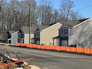 Row of modern homes under construction in Cramer Estates by D.R. Horton, Gastonia, NC, with tree-lined backdrop and sunny skies.