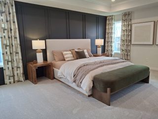 Model Home A cozy bedroom with a dark accent wall, modern wooden furniture, and elegant patterned curtains.