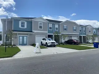 Two-story modern townhomes with blue accents and garages in Mill Creek North Townhomes by Lennar (Jacksonville, FL).