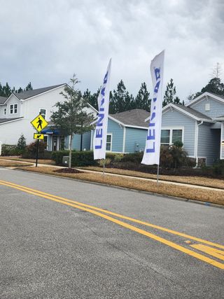 Charming blue and white home with Lennar flags, nestled in Tributary Royal Collection by Lennar (Yulee, FL).