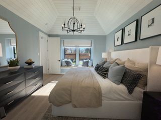 A serene bedroom with vaulted ceiling, chic chandelier, cozy window seat, and stylish decor.