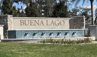 An elegant stone entrance with fountains and lush landscaping in Buena Lago Modern by D.R. Horton (St. Cloud, FL).
