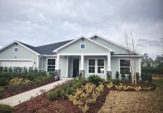 Charming home with gray siding, white trim, and lush landscaping in Tributary 70' by David Weekley Homes (Yulee, FL).