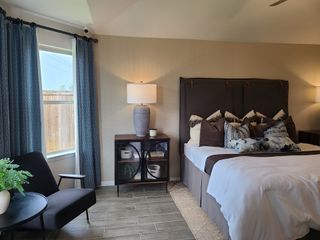 Cozy bedroom with a plush bed, elegant blue curtains, modern chair, and stylish accents creating a serene retreat.