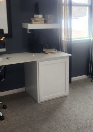 Model Home A sophisticated home office with deep blue walls, natural light, and a sleek built-in desk.