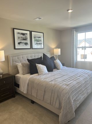 Model Home A cozy bedroom featuring a tufted bed, soft linens, dual nightstands, and modern art adorns the neutral-toned walls.