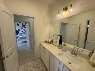 Model Home A chic bathroom with a stone countertop, double doors, and sleek lighting, leading to a playful bedroom.
