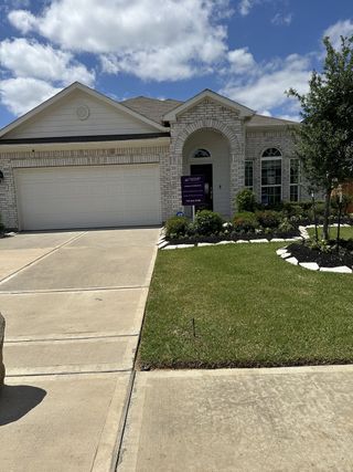 Elegant white brick home with arched entry and manicured yard in Willow Trace 45' by Century Communities (Spring, TX).