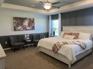 A cozy bedroom featuring a white bed, modern art, elegant trim, and neutral tones with stylish lighting and seating.