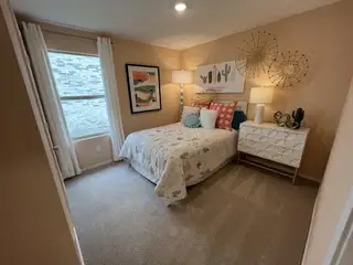 Model Home A vibrant bedroom with soft peach walls, playful decor, and a cozy atmosphere.