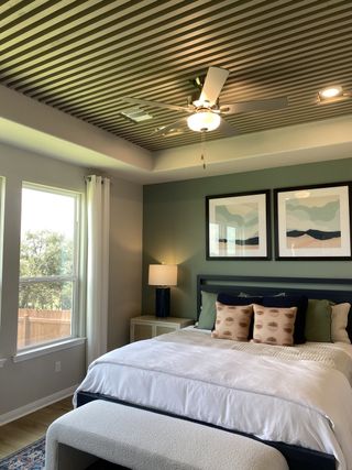 A cozy bedroom featuring a striped ceiling, stylish decor, and ample natural light from large windows.