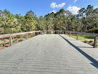 A spacious wooden deck surrounded by lush greenery and clear blue skies. Harmony West by D.R. Horton (St. Cloud, FL).
