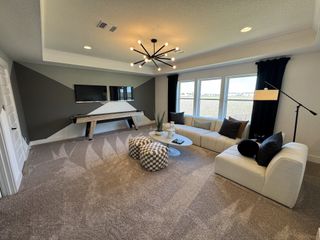 A modern living room with a geometric accent wall, sleek lighting, plush seating, and a shuffleboard table.